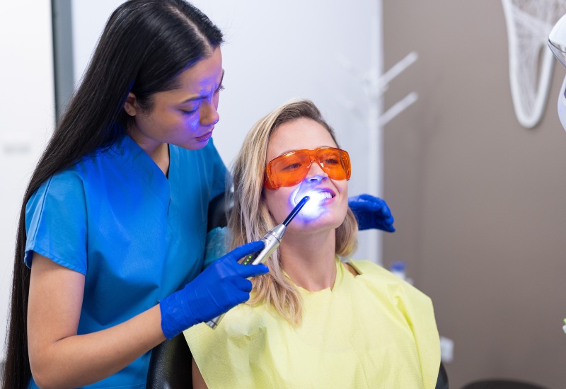 Dentist using curing light for teeth whitening in St. Charles, Glen Ellyn, IL.