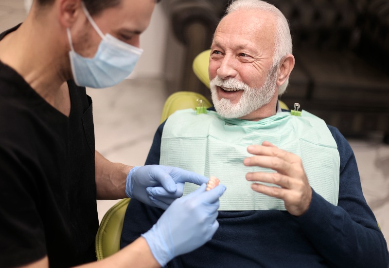 Dentist shows dentures to smiling patient in St. Charles & Glen Ellyn, IL